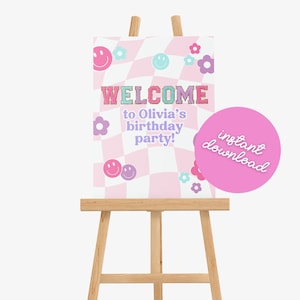 Op de afbeelding: Een roze en wit geruit welkomsbord met een paars en roze smiley-ontwerp. Het bord zegt "Welkom op Olivia's verjaardagsfeest!" en heeft een roze cirkel met de tekst "direct downloaden".