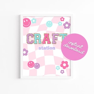 Może przedstawiać: Drukowana tabliczka z różowo-białym szachownicowym tłem. Tabliczka zawiera napis "CRAFT station" w kolorowych literach z brokatem. Tabliczka zawiera również różowe kwiaty i uśmiechnięte buźki.