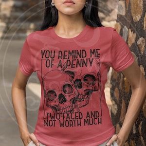 May include: Red t-shirt with a black skull graphic and the text "You remind me of a penny, two-faced and not worth much."