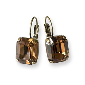 May include: A pair of gold-toned earrings with brown emerald-cut crystal stones.