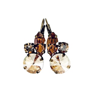 May include: A pair of dangle earrings with a cluster of brown and clear crystal stones. The earrings have a gold-tone finish.