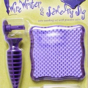 May include: Purple plastic tool with a handle and a pointed tip, a purple square practice pad with holes, and a spool of purple wire. The packaging says "Artistic Wire's Wire Writer & Jewelry Sig wire working set with practice wire".