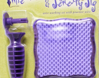 May include: Purple plastic tool with a handle and a pointed tip, a purple square practice pad with holes, and a spool of purple wire. The packaging says "Artistic Wire's Wire Writer & Jewelry Sig wire working set with practice wire".