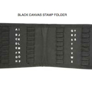 May include: Black canvas stamp folder, open and laid flat. The folder has multiple pockets for stamps, with white lettering indicating stamp categories. The text "BLACK CANVAS STAMP FOLDER" is at the top.