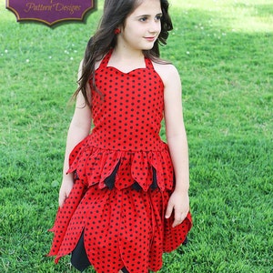 May include: A young girl wearing a red and black polka dot dress with a layered skirt. The dress has a halter neckline and is styled with black accents. The dress is called "Fairy Tale Pattern Designs".