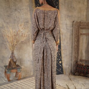 May include: A long, flowing dress with a brown and black zebra print. The dress has a V-neck and long sleeves. The dress is tied at the waist with a brown belt.