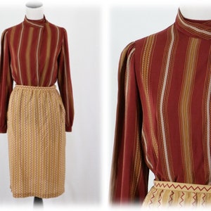 May include: A striped blouse with a high collar and long sleeves, paired with a matching skirt. The blouse and skirt are both in shades of brown, beige, and white.