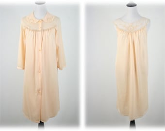 May include: A pale peach-colored nightgown with a lace trim around the neckline. The nightgown has a button-up front and 3/4 sleeves.
