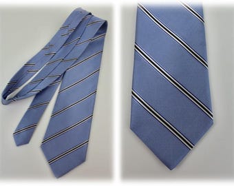 May include: A light blue tie with diagonal stripes in black and white. The tie is made of a textured fabric and is displayed in two views, one fully extended and the other showing the knot.