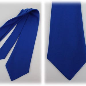 May include: A royal blue necktie, displayed in two views. One shows the tie fully extended, while the other presents a close-up of the fabric. The tie is made of a smooth, solid-colored material, suitable for formal or business attire.