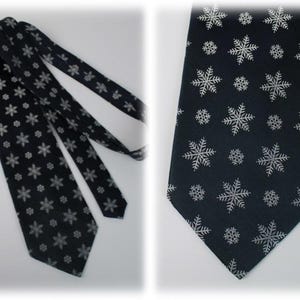 May include: A black necktie with a white snowflake pattern. The tie is shown folded and laid flat.