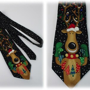 May include: A black tie with a white snowflake pattern and a cartoon reindeer wearing a Santa hat and holding presents. The reindeer is smiling and has a red nose.