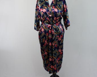 May include: A navy blue satin robe with a floral print featuring pink, green, and gold accents. The robe has a tie belt and long sleeves.