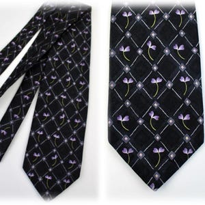 May include: Black necktie with a repeating pattern of purple flowers and white diamond shapes. The tie has a classic design and is suitable for formal or business attire. The tie is made of a smooth fabric.