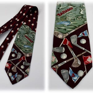 May include: A dark maroon necktie featuring a repeating pattern of golf clubs, white golf balls, and red, blue, and green flags with the Tabasco logo. The top section displays a green golf course landscape with the red text Tabasco printed across it.