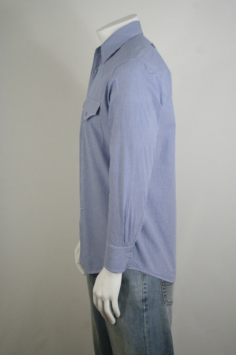 May include: A blue and white checkered long-sleeve shirt with a button-down collar and a single chest pocket.