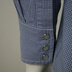 May include: A blue and white gingham shirt with a long sleeve and four silver buttons on the cuff.