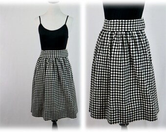 May include: Black and white checkered skirt with a high waist and a gathered design. The skirt is knee-length and has a fitted silhouette.
