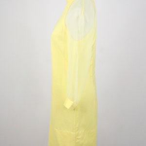 May include: A yellow dress with sheer sleeves. The dress has a high neckline and a fitted silhouette.