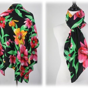 May include: A black floral scarf with pink, yellow, and green flowers. The scarf is shown tied around a mannequin's neck.