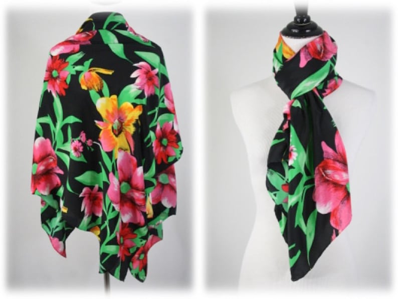 May include: A black floral scarf with pink, yellow, and green flowers. The scarf is shown tied around a mannequin's neck.