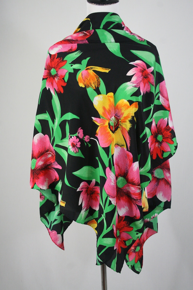 May include: A black triangular scarf with a floral print featuring pink, red, yellow, and green flowers on a black background.