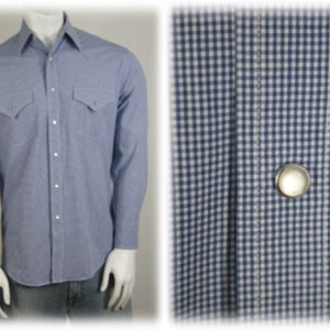 May include: A light blue long-sleeved shirt with a white and blue gingham pattern. The shirt has a button-down collar, two chest pockets, and a single button closure at the front.