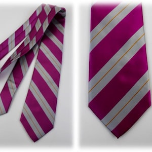 May include: A necktie featuring a vibrant magenta background with diagonal silver stripes and thin gold pinstripes. The tie is shown in two views, one folded and one laid flat, displaying the pointed end and the consistent striped pattern throughout.