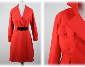May include: A red, long-sleeved, collared dress with a black belt and a flap pocket on the left side.