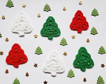 Puede incluir: Una colección de apliques de árbol de Navidad de ganchillo en blanco, verde y rojo, intercalados con pequeños botones de madera con forma de estrellas y árboles de Navidad verdes, dispuestos en un patrón disperso sobre una superficie blanca.