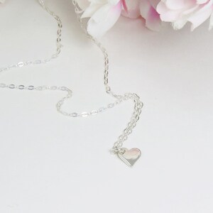 May include: A silver chain necklace with a small silver heart pendant.