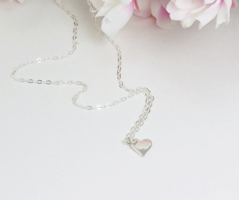 May include: A silver chain necklace with a small silver heart pendant.