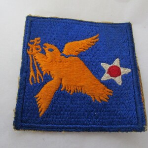 May include: A blue embroidered patch with an orange bird holding a trident and a white star with a red center.
