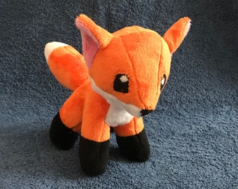 May include: A plush orange fox toy with black feet and a white chest. The fox has large black eyes and a pink nose.