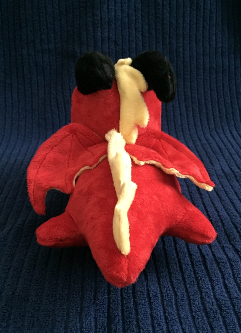 Overhead view of red dragon plushie showing wings, black horns, and yellow spikes