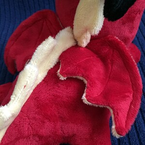 Close up of red dragon plushie showing the wing top stitching details
