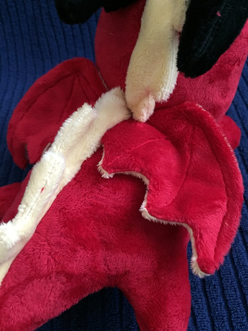 Close up of red dragon plushie showing the wing top stitching details