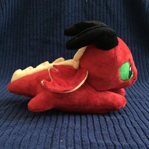 Side view of red dragon plushie showing wings and light yellow spikes
