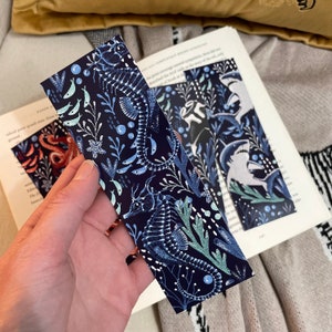 May include: A blue bookmark with a white and light blue seahorse design. The bookmark features a repeating pattern of seahorses, seaweed, and bubbles.