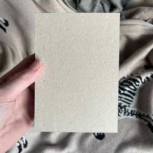Puede incluir: Una tarjeta en blanco, de color marr&oacute;n claro, sostenida en una mano. La tarjeta est&aacute; hecha de papel texturizado.