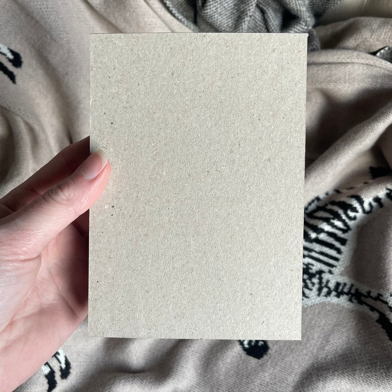 Puede incluir: Una tarjeta en blanco, de color marr&oacute;n claro, sostenida en una mano. La tarjeta est&aacute; hecha de papel texturizado.