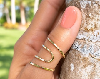 Peut inclure: Une bague dorée présentant un design en spirale continue qui s'enroule autour du doigt. Le métal possède une finition lisse et polie avec un anneau fin et arrondi créant une apparence superposée et ouverte sur le doigt.