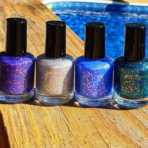 May include: Four bottles of nail polish with different colors and glitter. The colors are purple, silver, blue, and green.