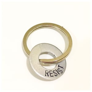 May include: A silver key chain with a round metal tag that says "RESIST" on it.