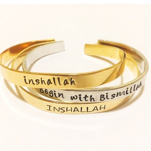 May include: Three gold bracelets with the words "inshallah", "begin with", and "Bismillah" engraved on them.