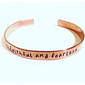 Puede incluir: Una pulsera de cobre con las palabras "fiel e intrépido" grabadas.