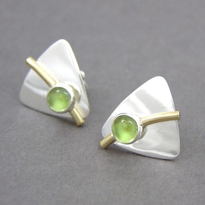 May include: A pair of silver triangle earrings with a gold bar and a green gemstone in the center.