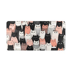 May include: A rectangular mat featuring a repeating pattern of cartoon cats. The cats are in various colors, including black, white, pink, and gray. The cats have different expressions and poses, creating a playful and whimsical design.