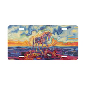 May include: A license plate featuring a colorful painting of a horse. The horse is depicted in vibrant blues, reds, and yellows, set against a swirling sunset background. The plate has four mounting holes.