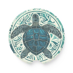 May include: A round car coaster featuring a detailed illustration of a sea turtle in shades of teal and blue. The turtle is centered within a decorative, swirling pattern on a cream-colored background.
